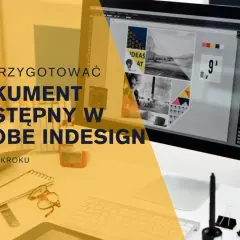 Na biurku komputer z programem Adobe InDesign, na którym tworzony jest projekt. Obok notatnik, okulary i przybory biurowe.