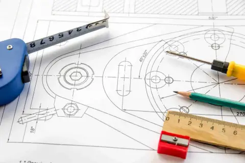 Precyzyjny projekt graficzny z miarką, ołówkiem i śrubokrętem na rysunku technicznym.
