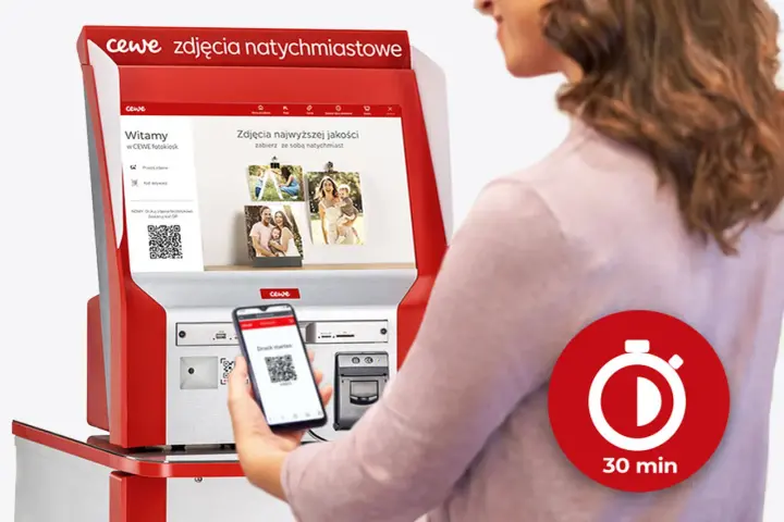Kobieta korzysta z fotokiosku CEWE w Rossmannie, skanując kod QR telefonem, by wydrukować zdjęcia w 30 minut.