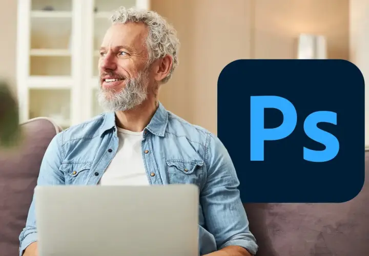Uśmiechnięty mężczyzna z siwą brodą siedzi z laptopem, obok logo Photoshop. Dowiedz się, psd co to jest i jak go używać.