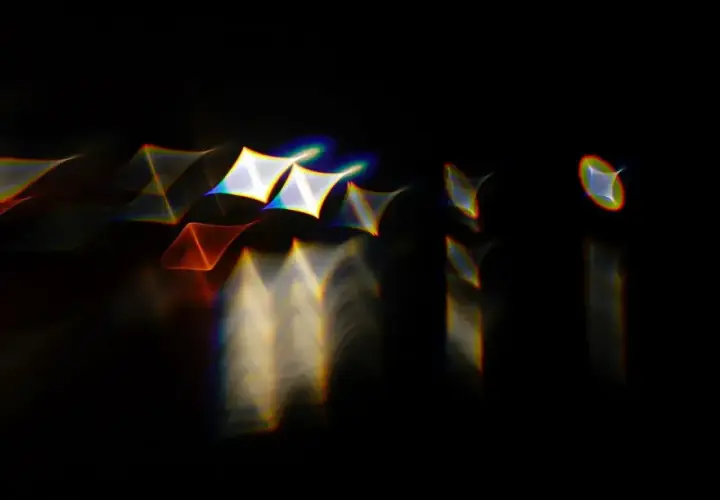 Rozmyte kształty przypominające gwiazdy i trójkąty, otoczone tęczowymi obwódkami, efekt **chromatic aberration**.