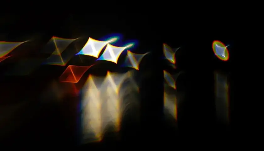 Rozmyte kształty przypominające gwiazdy i trójkąty, otoczone tęczowymi obwódkami, efekt **chromatic aberration**.