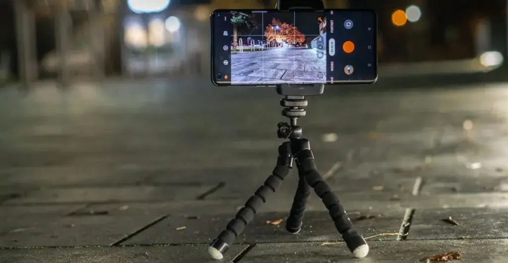 osoba fotografująca smartfonem na statywie pod nocnym niebem