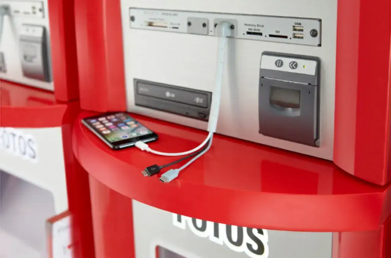 Cewe Rossmann: iPhone podłączony do fotokiosku, gotowy do druku zdjęć.