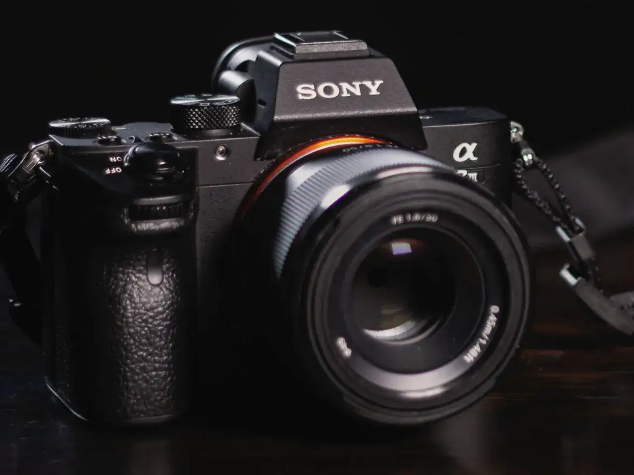 Czarna lustrzanka Sony Alpha z obiektywem 50mm f/1.8. Idealna używana lustrzanka dla początkujących, gotowa do uchwycenia pierwszych kadrów.